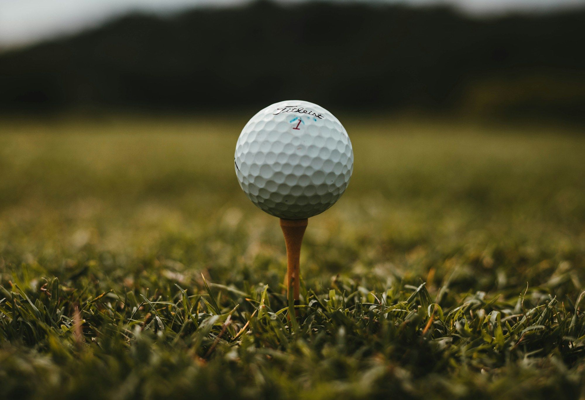Golfball liegt auf einem Holz-Tee auf dem Abschlag