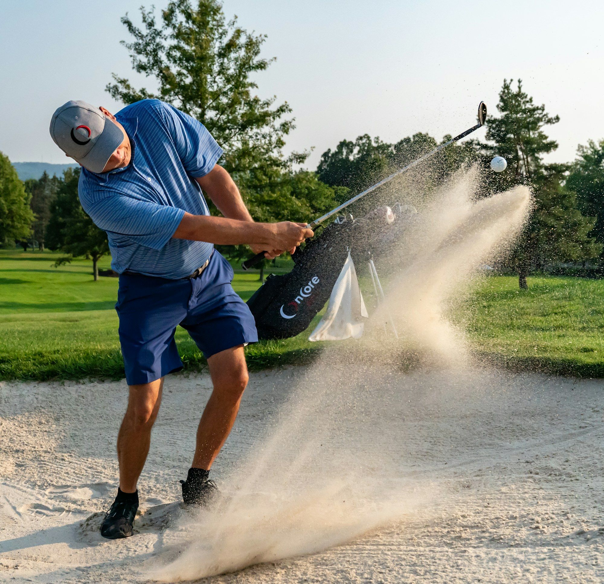 Golfer schlägt aus einem Sandbunker und wirbelt eine Sandwolke auf