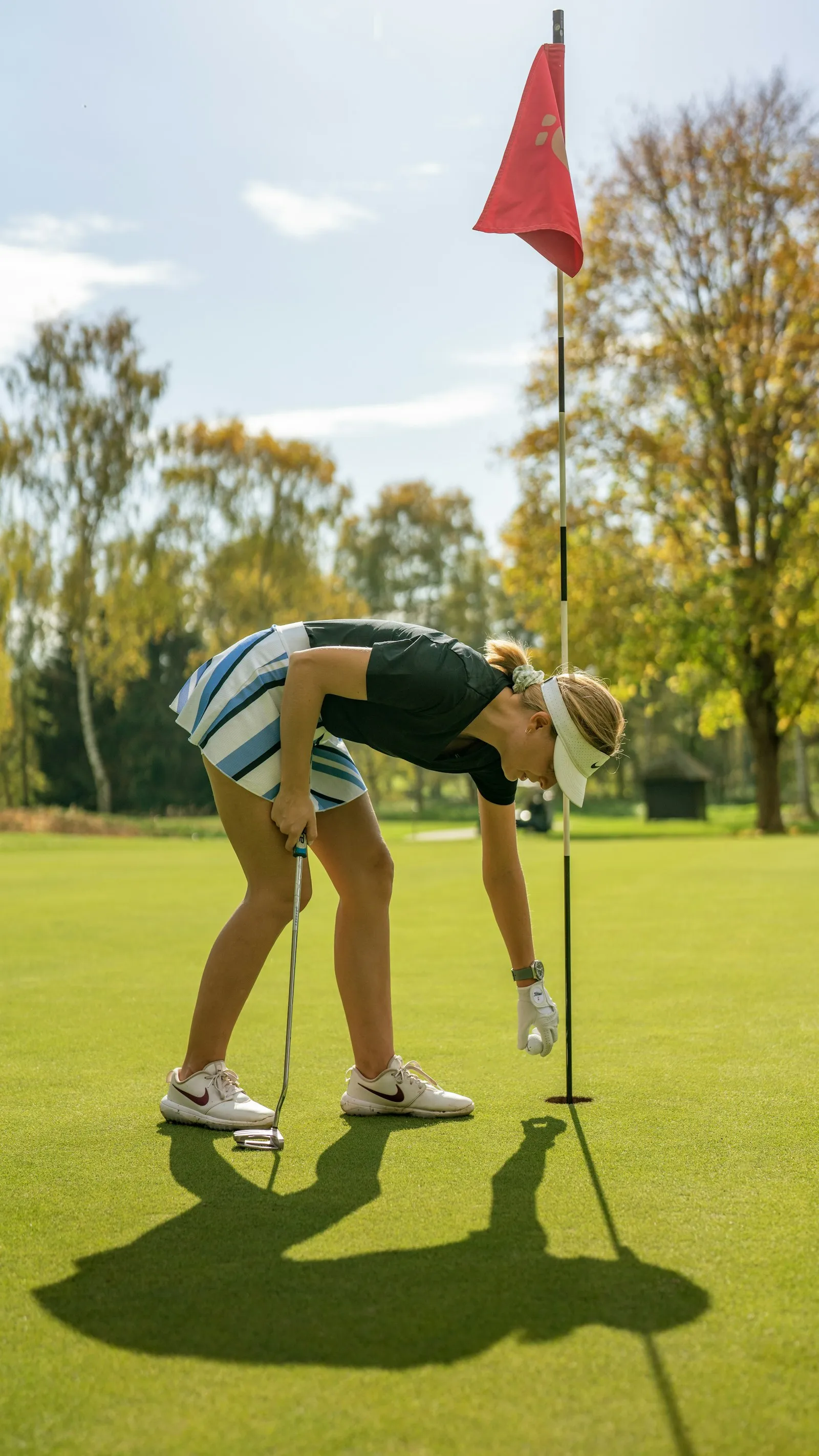 Golferin beim Putten auf einem Grün