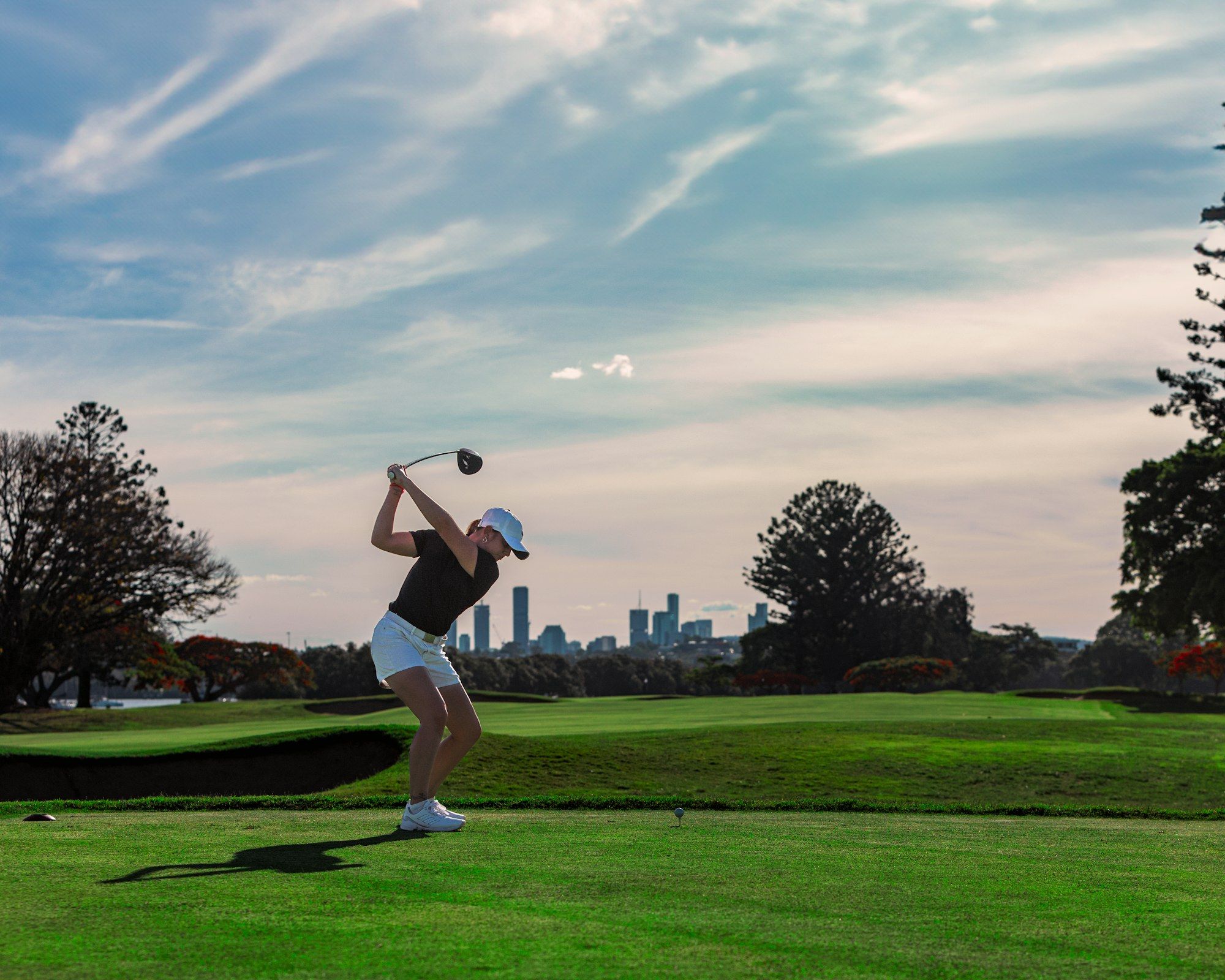 Golferin führt auf der Driving Range einen Schwung mit dem Eisen aus
